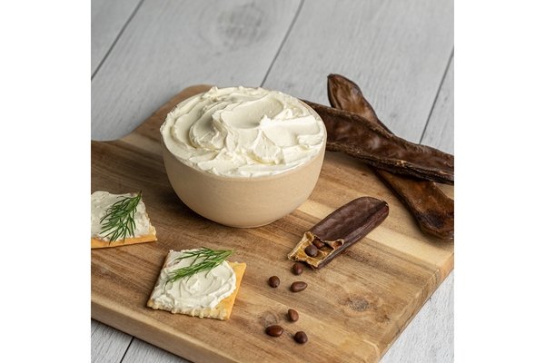Locust bean and an alternative dairy spreadable cheese on cutting board.